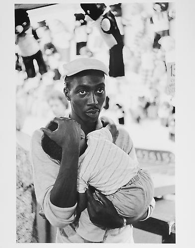 Man holding baby at street festival 
mid 1950s
Gelatin Silver Print