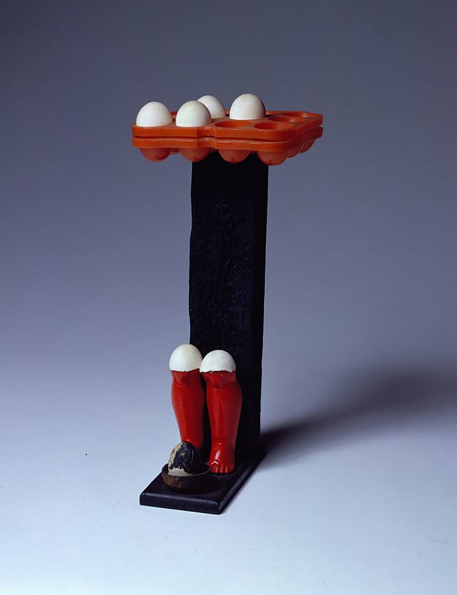 Marcel Broodthaers		(1924 - 1976)<br />Untitled<br />1964<br />paint on wood, plastic, doll's legs, and eggs<br />19 x 8 1/4 x 9 inches <br />(48.26 x 20.96 x 22.86 cm)<br />