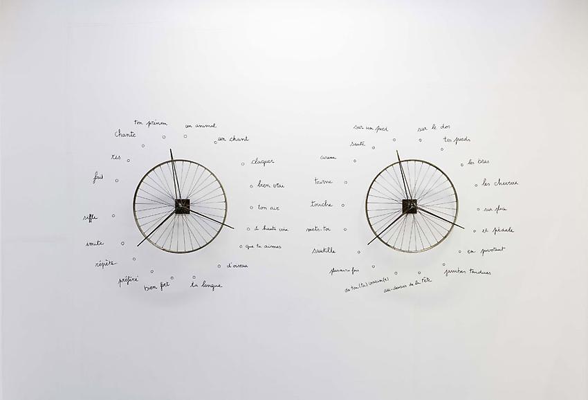 Robert Filliou<br />Danse-poème collectif<br />(à performer deux par deux, chacun(e) tournant<br />une roue)<br />[Replica of a 1962 performance]<br />1962<br />2 metal wheels and marker on wall<br />wheels: diameter 25 1/4 inches each<br />(64 cm each)<br />